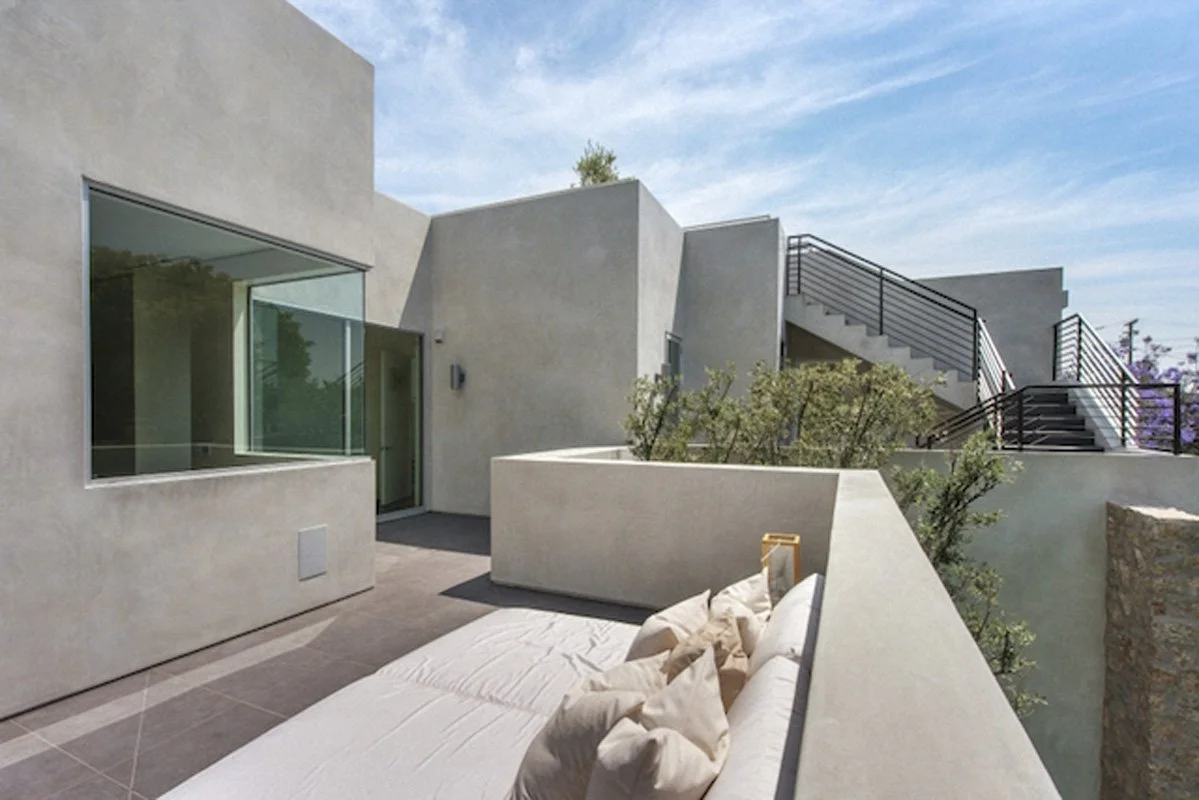 Private terrace outside bedroom in West Hollywood custom home with lounge seating and modern plaster walls.