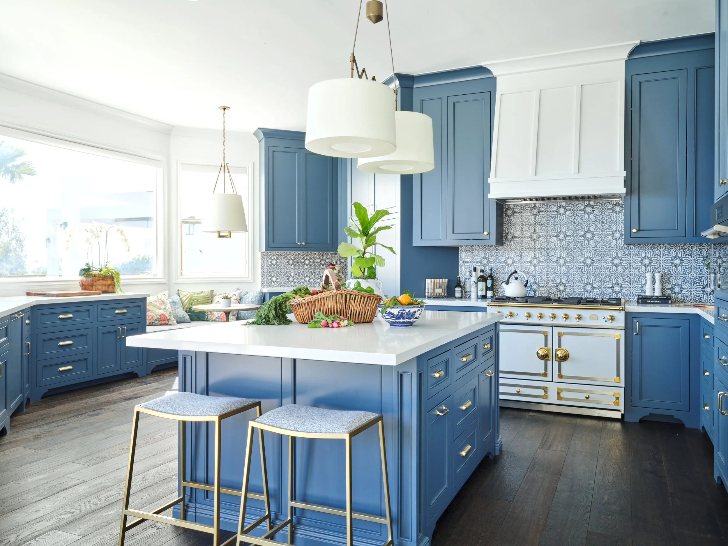 Malibu custom kitchen with blue cabinetry, large center island, brass hardware, patterned tile backsplash, and professional range built by Heart Construction