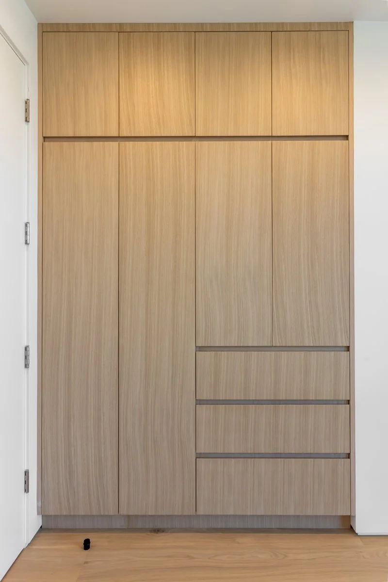 Custom Mar Vista built-in closet with floor-to-ceiling light wood cabinetry, minimalist flat-panel doors, integrated drawer storage, and seamless modern millwork in a contemporary custom home.