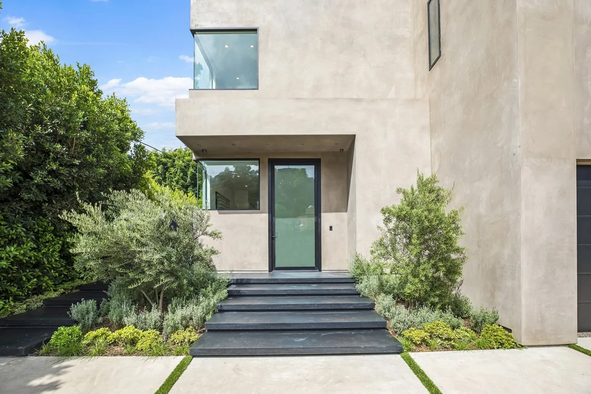 Beverly Hills custom home entry with dark stone steps, frosted glass door, and landscaped approach