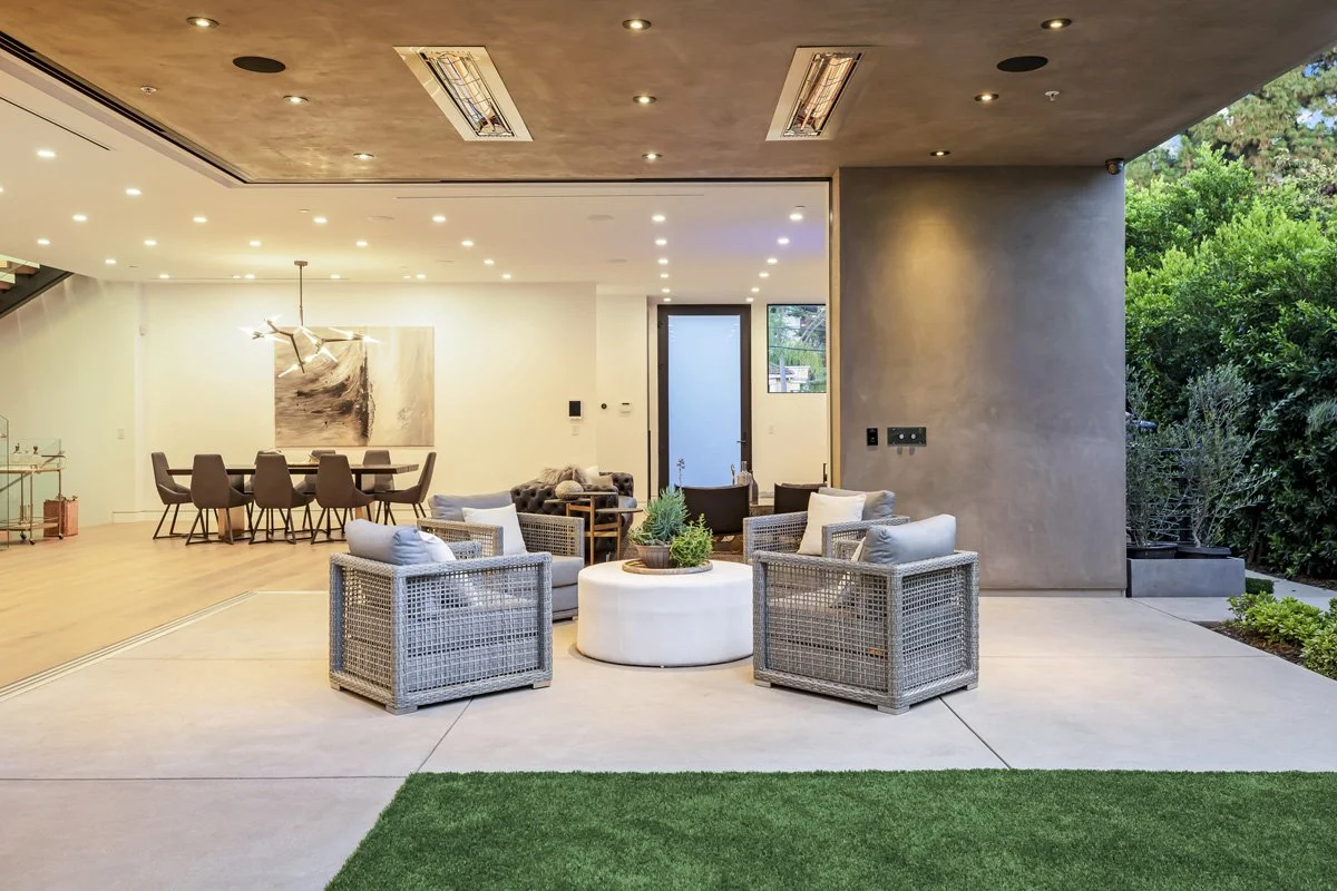 Beverly Hills indoor-outdoor living space at dusk with open-plan dining area and covered patio lounge