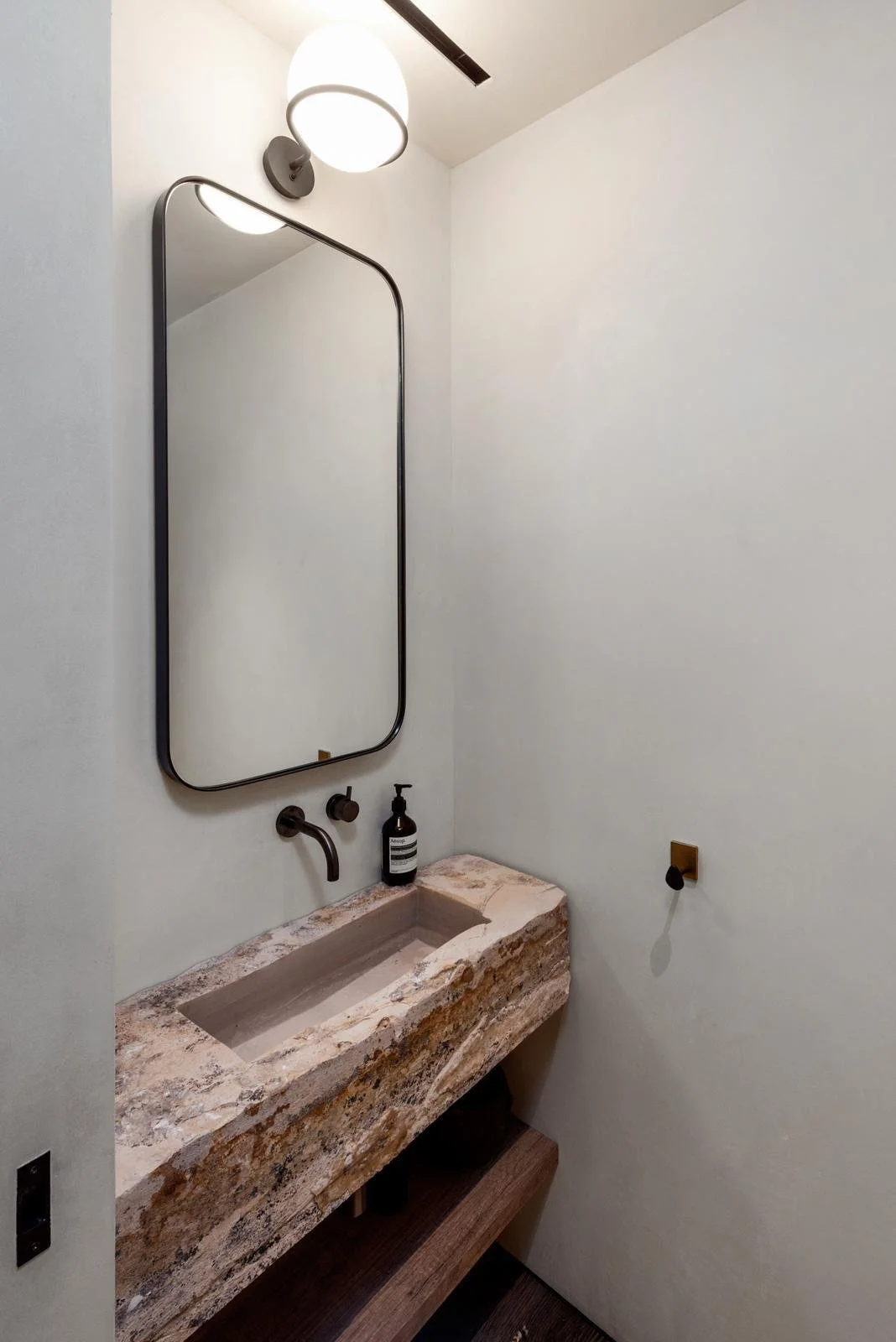 Malibu home powder room with stone vanity sink and wall-mounted faucet.