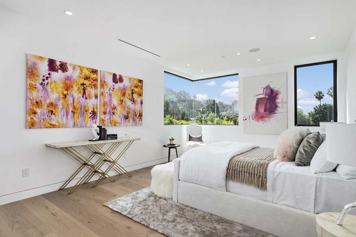 Beverly Hills bedroom with corner windows, contemporary artwork, and hillside views
