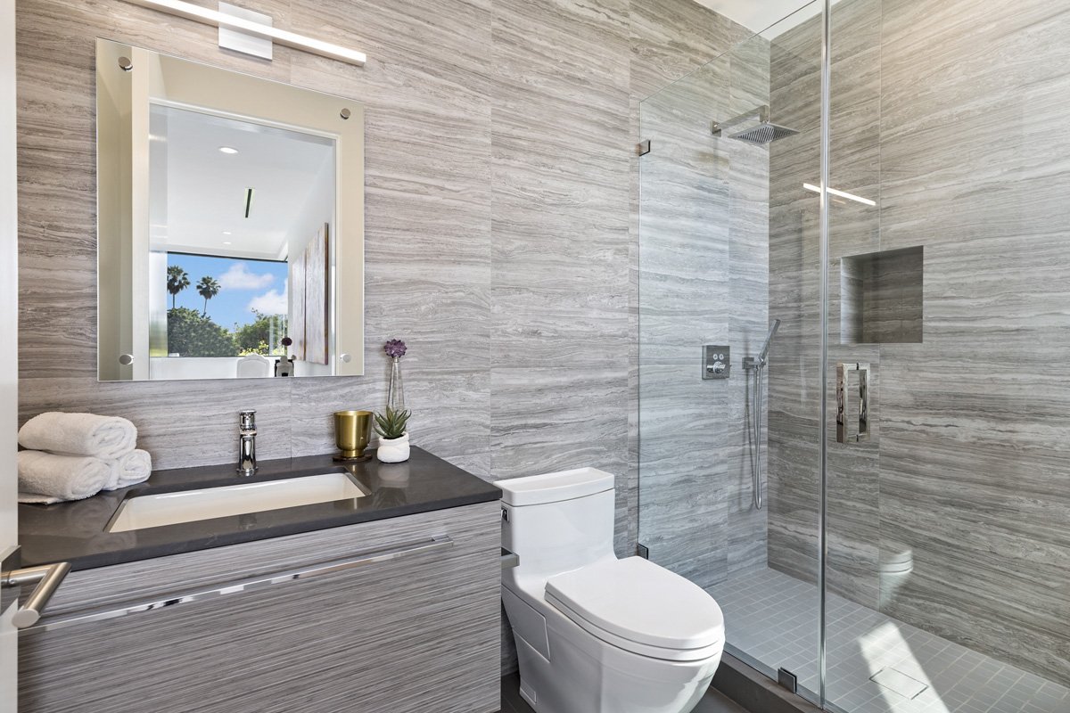 Beverly Hills contemporary bathroom with stone tile walls, floating vanity, and frameless glass shower