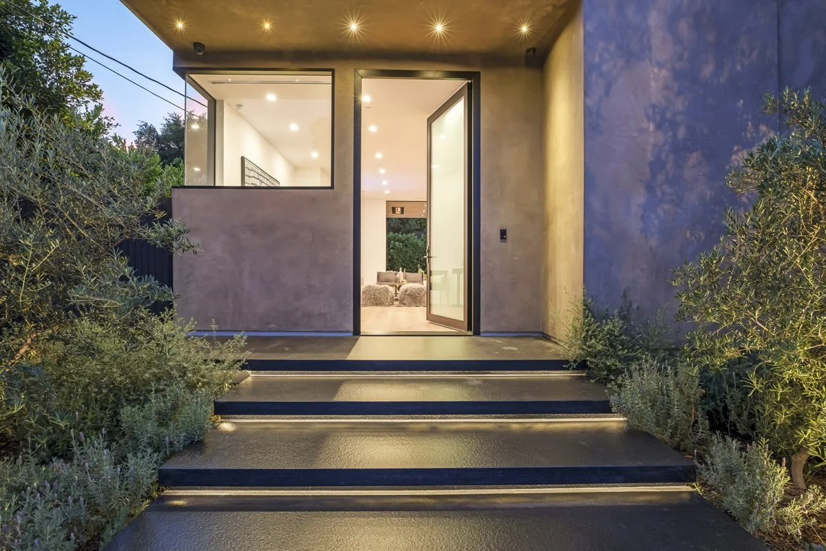 Modern Hollywood Hills home entry with custom front door, architectural lighting, and landscaped approach