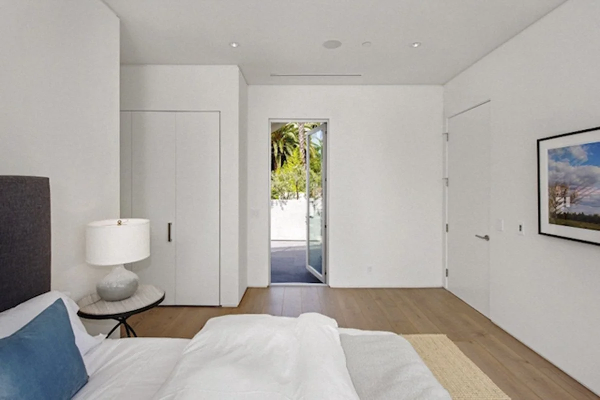 Bright bedroom with terrace access in West Hollywood modern home with natural wood flooring.