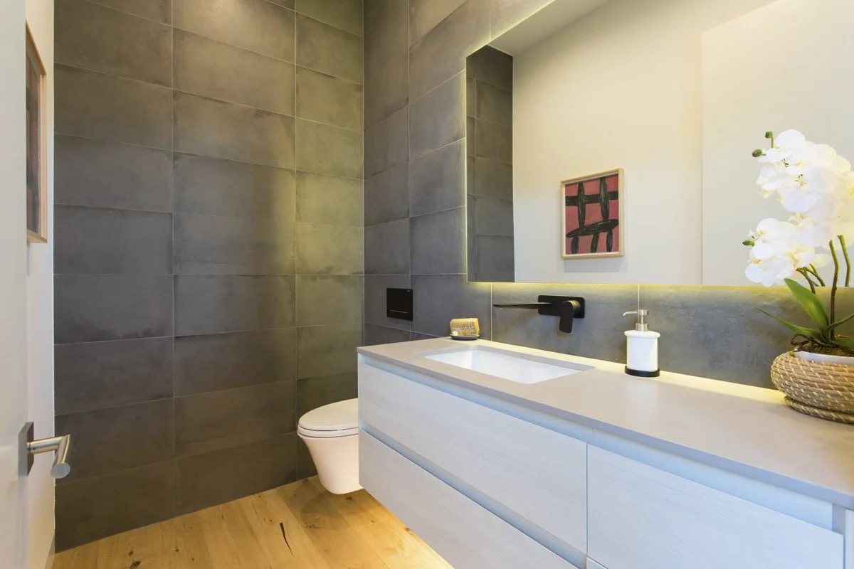 Venice contemporary powder room with large-format tile walls, floating vanity, integrated LED mirror lighting, and matte black fixtures