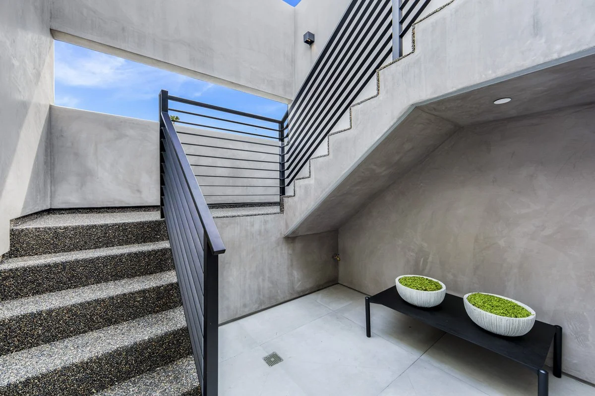 Modern concrete staircase with black steel railing in West Hollywood custom home