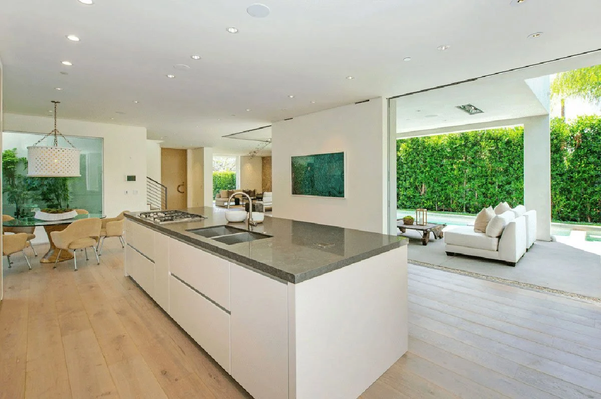 Open-plan kitchen and living space in West Hollywood modern home with sliding glass walls to pool.