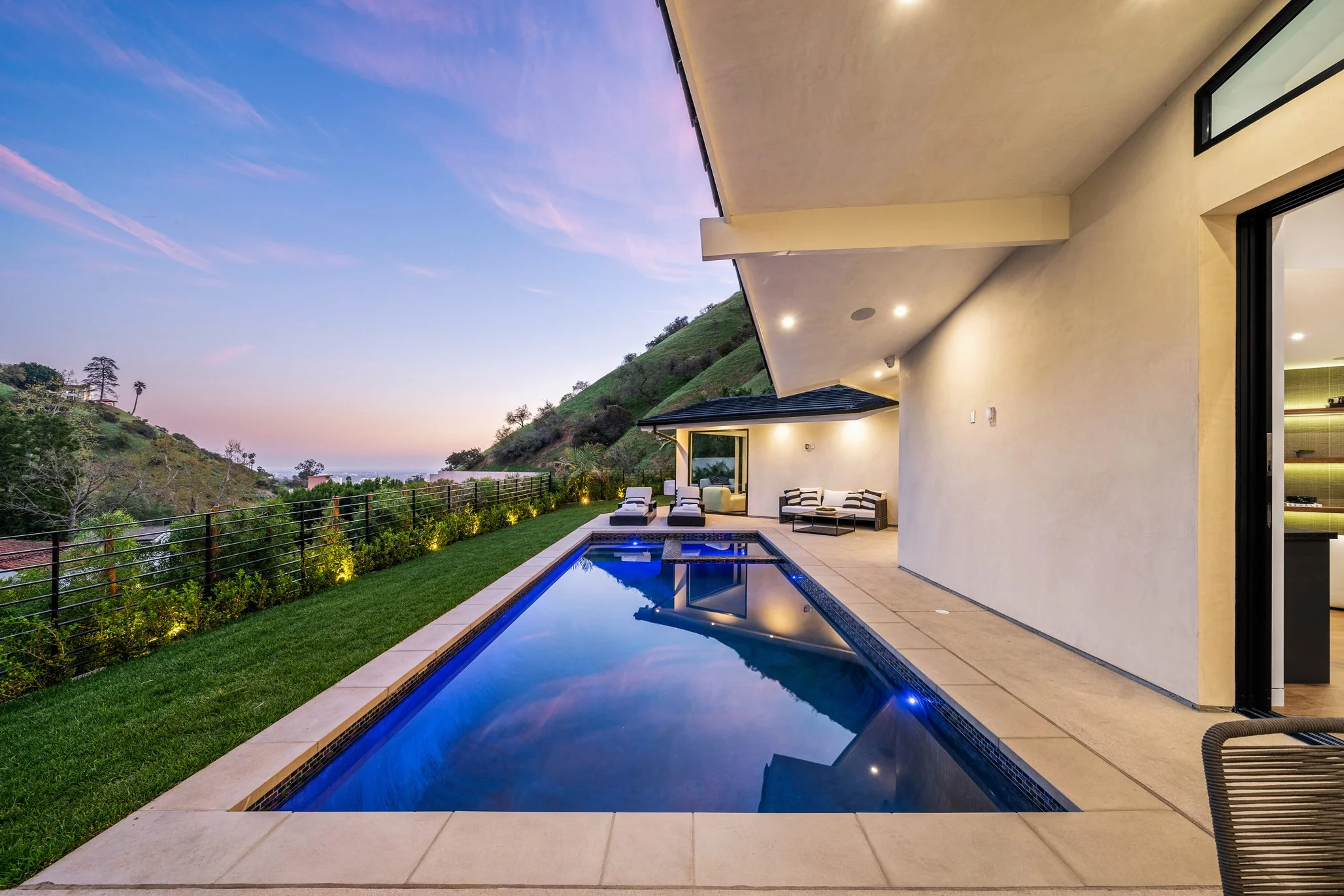 Luxury Hollywood Hills hillside home with modern pool, covered terrace, and panoramic canyon views at sunset