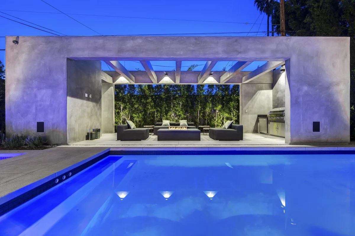 West Hollywood custom home outdoor pavilion with fire feature, modern lounge seating, and illuminated pool at night