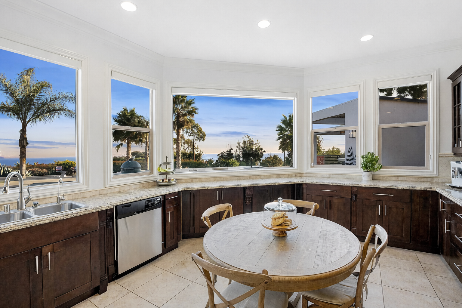 Before remodel kitchen with dark wood cabinets and ocean-view windows but disconnected layout and limited flow