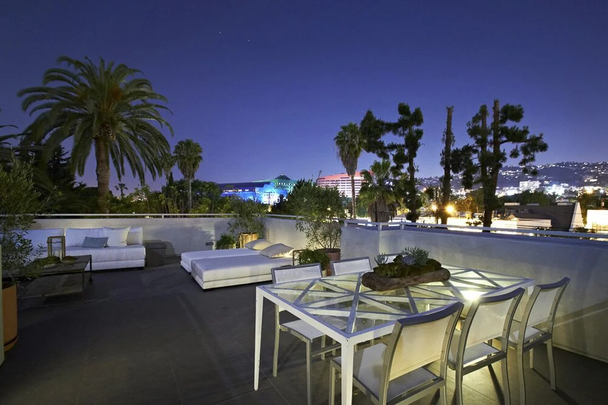 Night view of rooftop terrace in West Hollywood modern residence with lounge seating and city skyline.