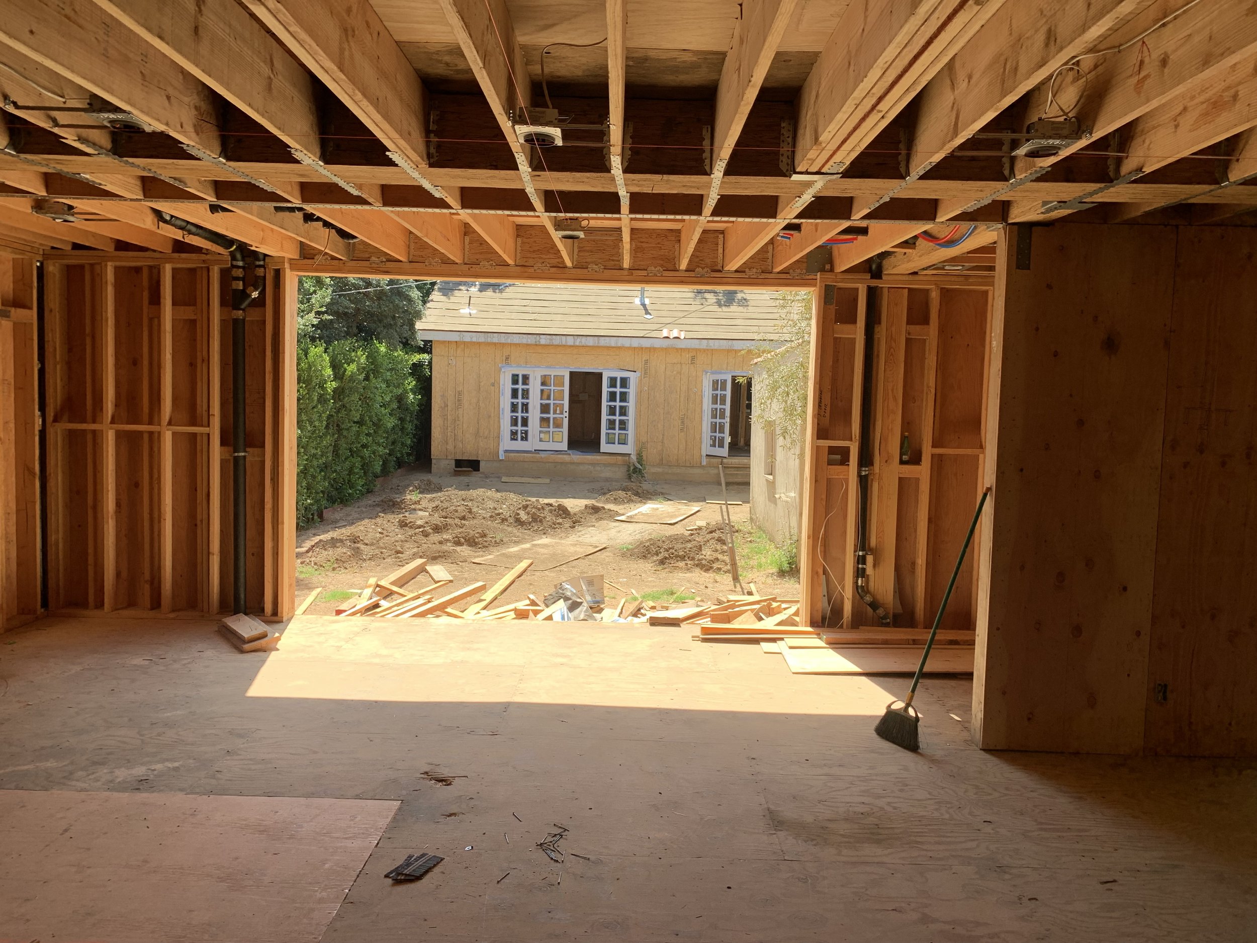 Hancock Park home remodel in progress showing exposed framing, structural opening to backyard, and early stage ADU construction