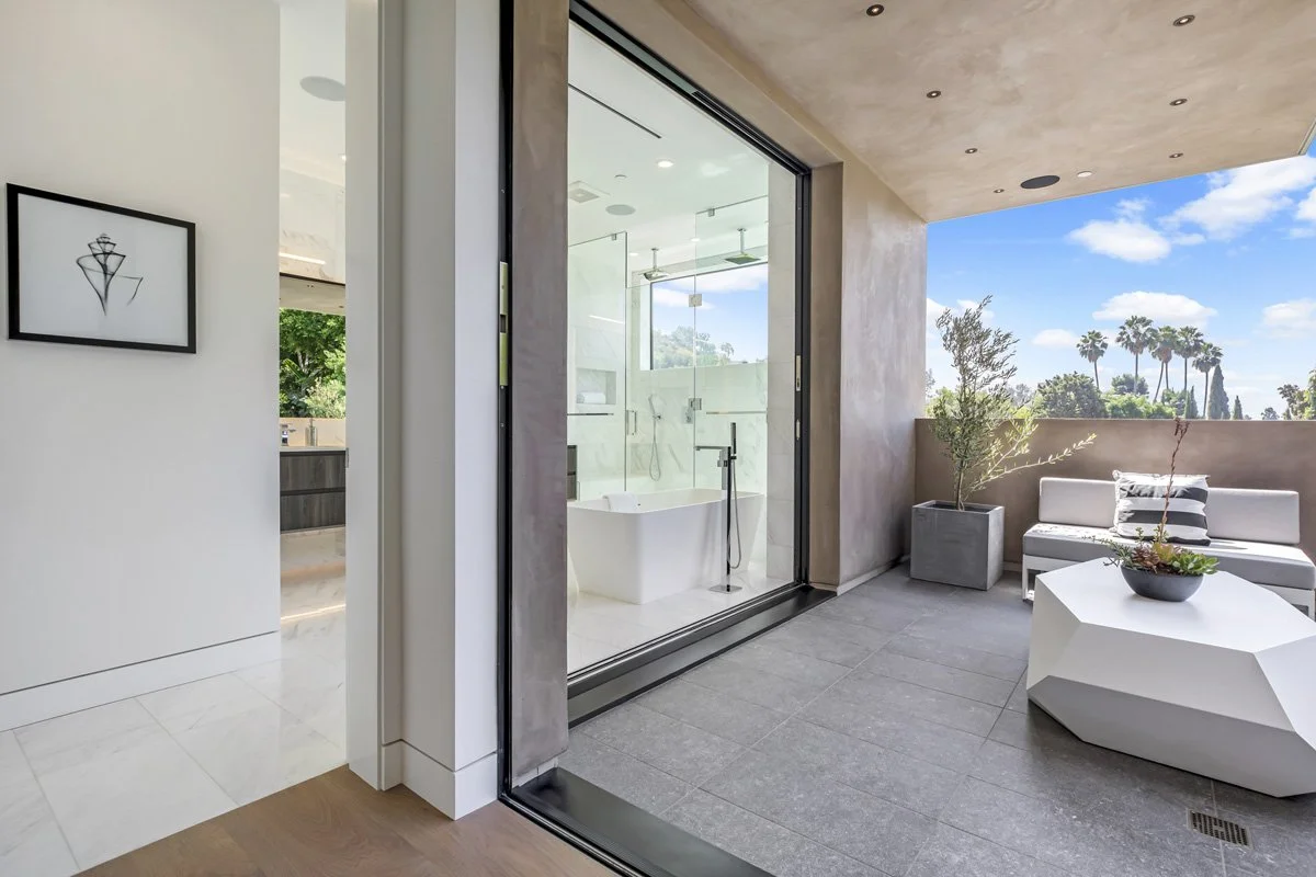 Beverly Hills primary bathroom opening to private terrace with freestanding soaking tub and marble tile