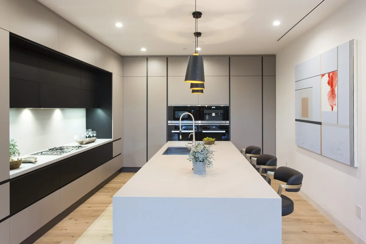 Contemporary kitchen with large island, integrated appliances, and modern pendant lighting