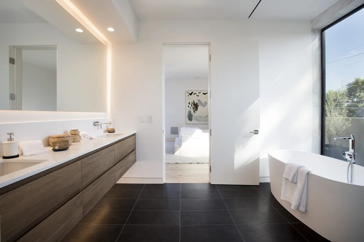 Minimalist bathroom with freestanding tub, floating vanity, and large mirror in modern Venice remodel