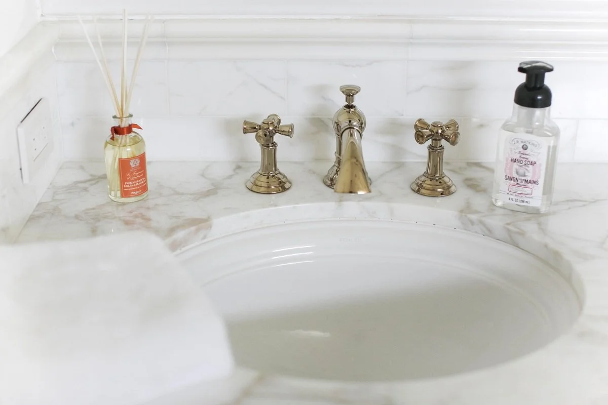 Bathroom sink detail with marble countertop and polished brass faucet in Hancock Park remodel