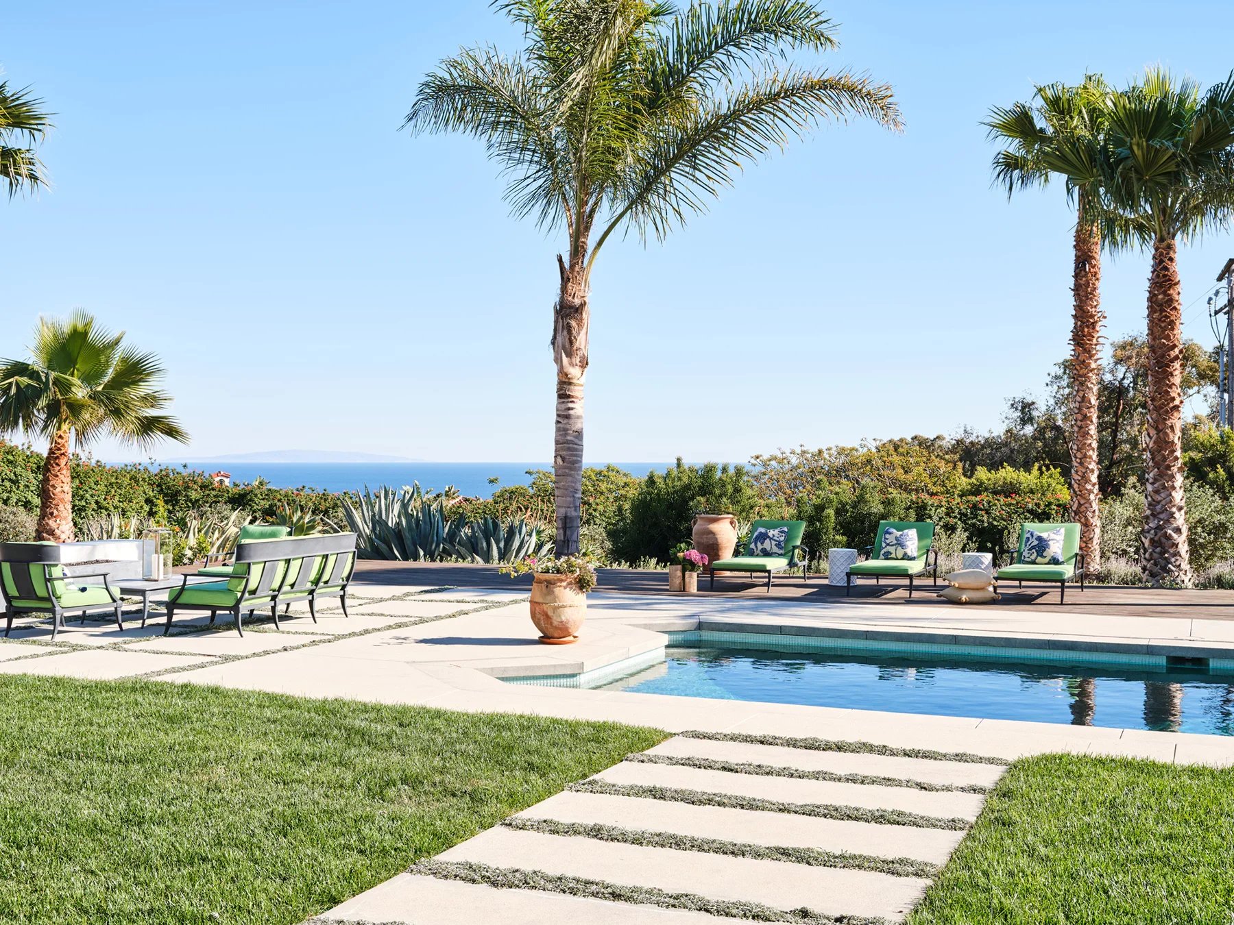 Malibu coastal home with ocean views, custom outdoor living space, pool, and palm-lined terrace