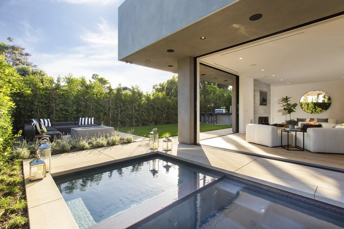 Modern indoor-outdoor living space opening to pool and landscaped backyard in Venice custom home