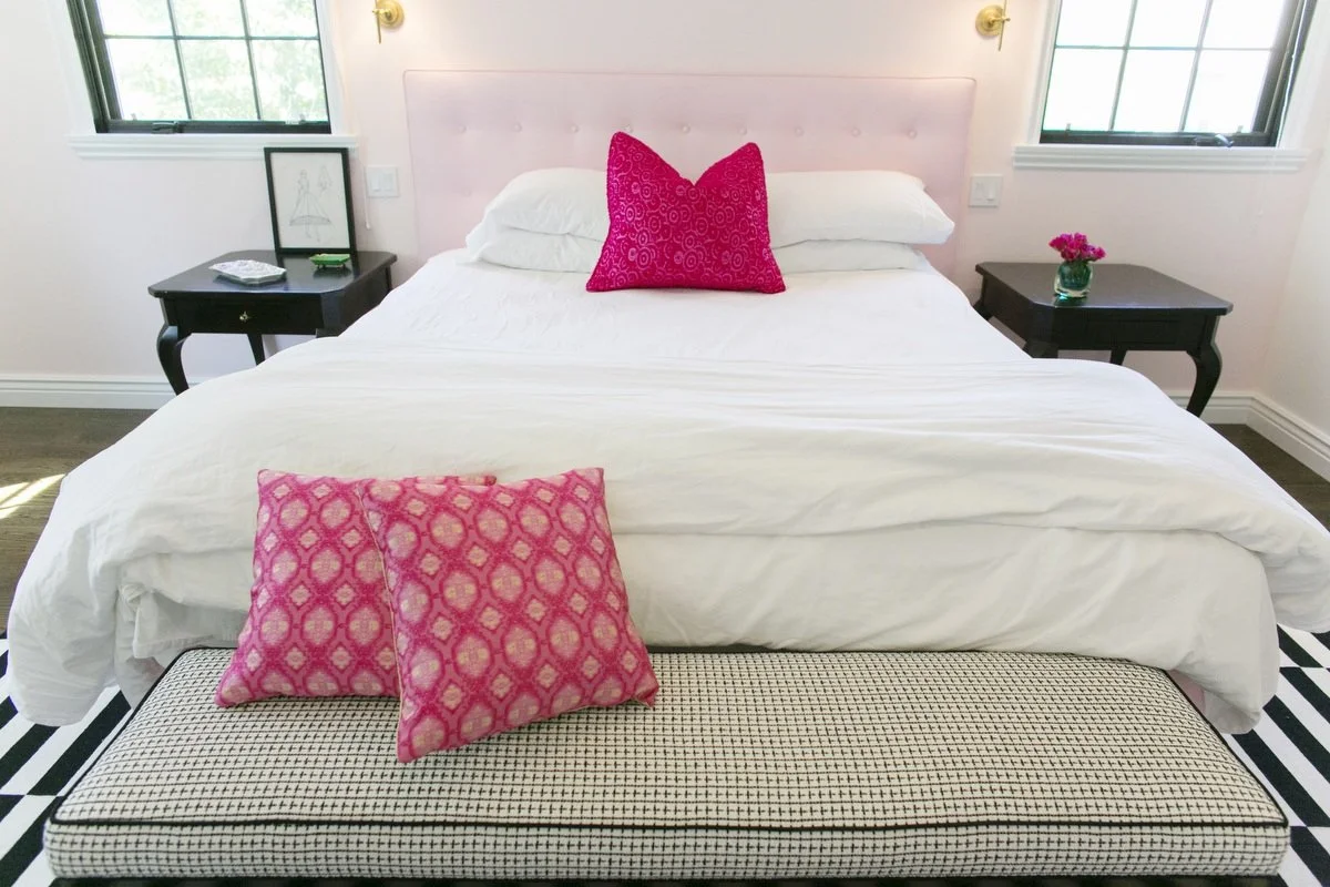 Bedroom detail with upholstered bench and patterned pillows at foot of bed