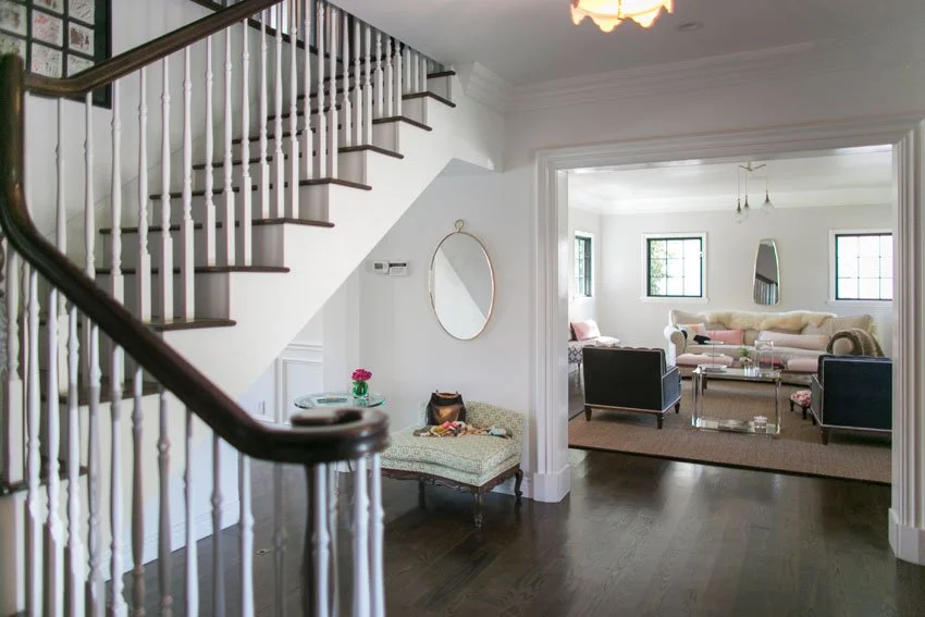 Entry hall with staircase, dark wood floors, and view into bright living room in Hancock Park home