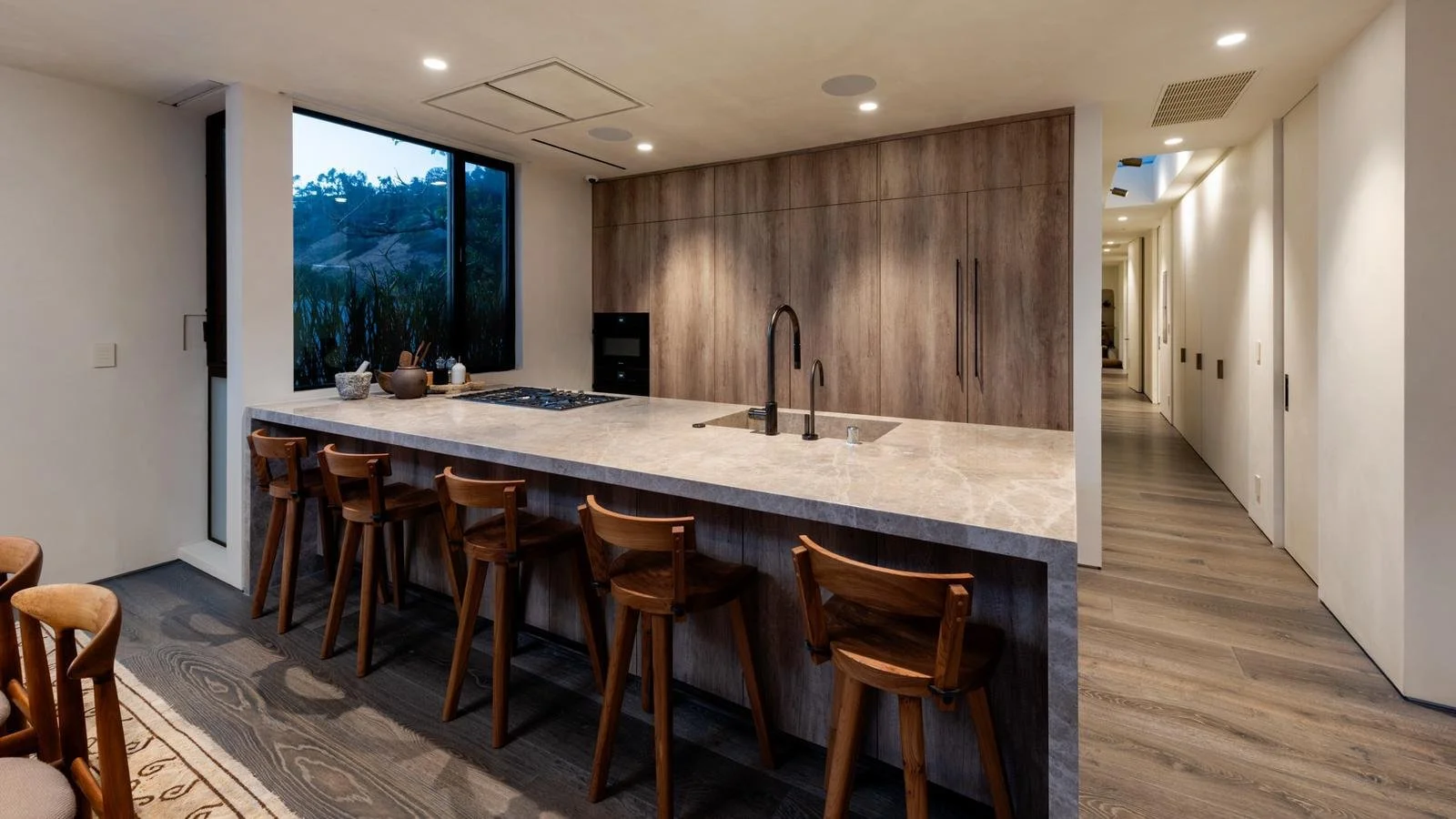 Modern Malibu kitchen with waterfall stone island and custom wood cabinetry.