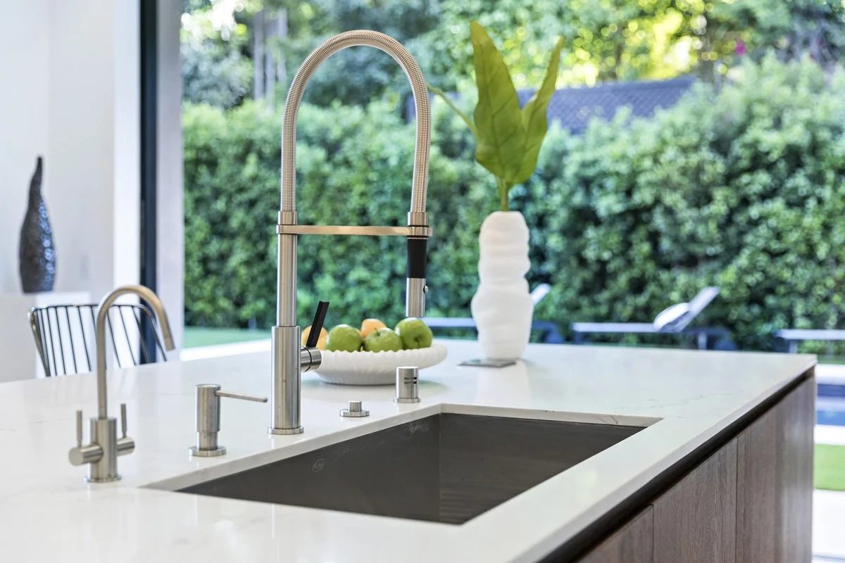 Beverly Hills kitchen island detail with brushed metal faucet, undermount sink, and backyard views