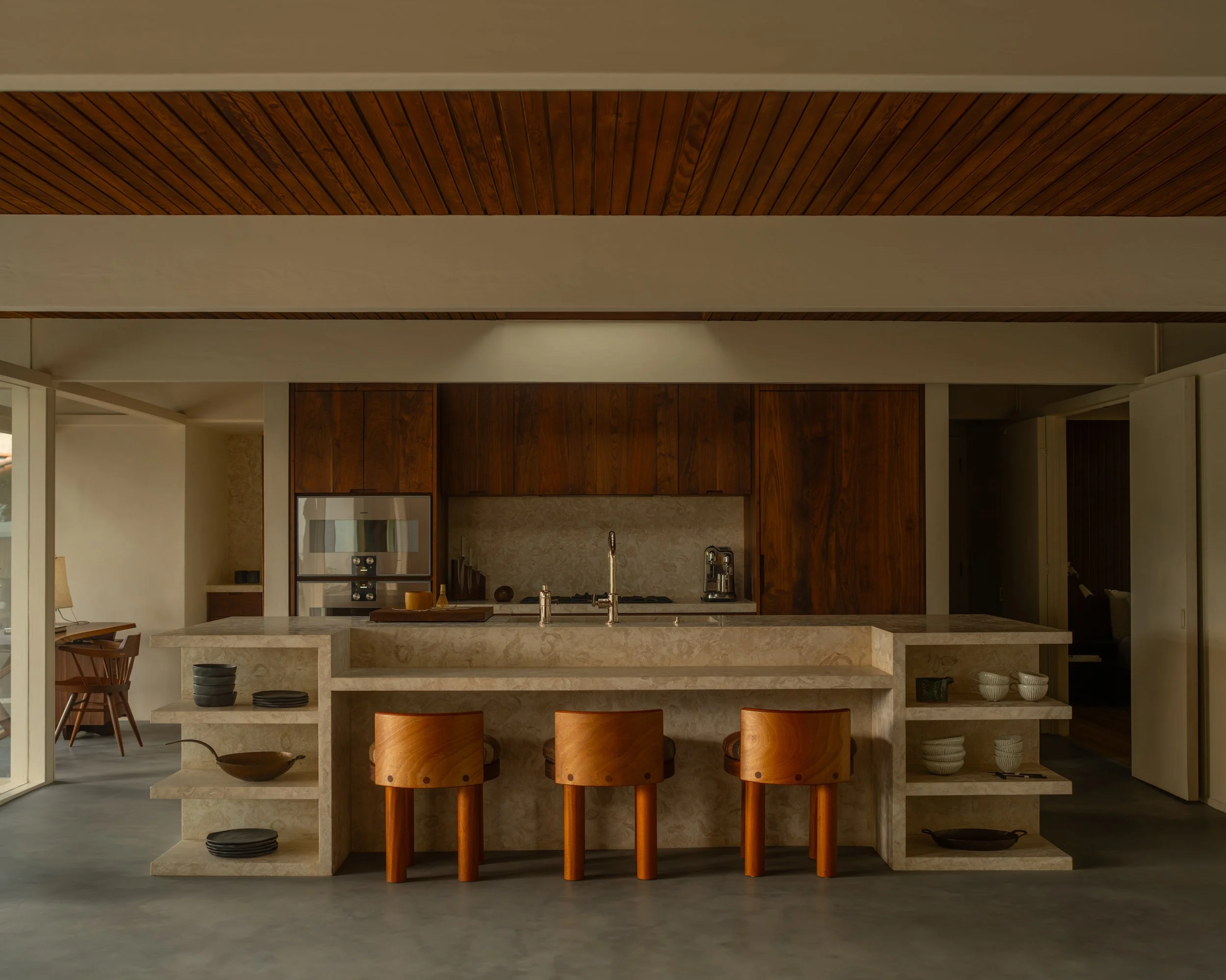 Brentwood custom kitchen with warm wood cabinetry, stone island with open shelving, and integrated high-end appliances by Heart Construction.