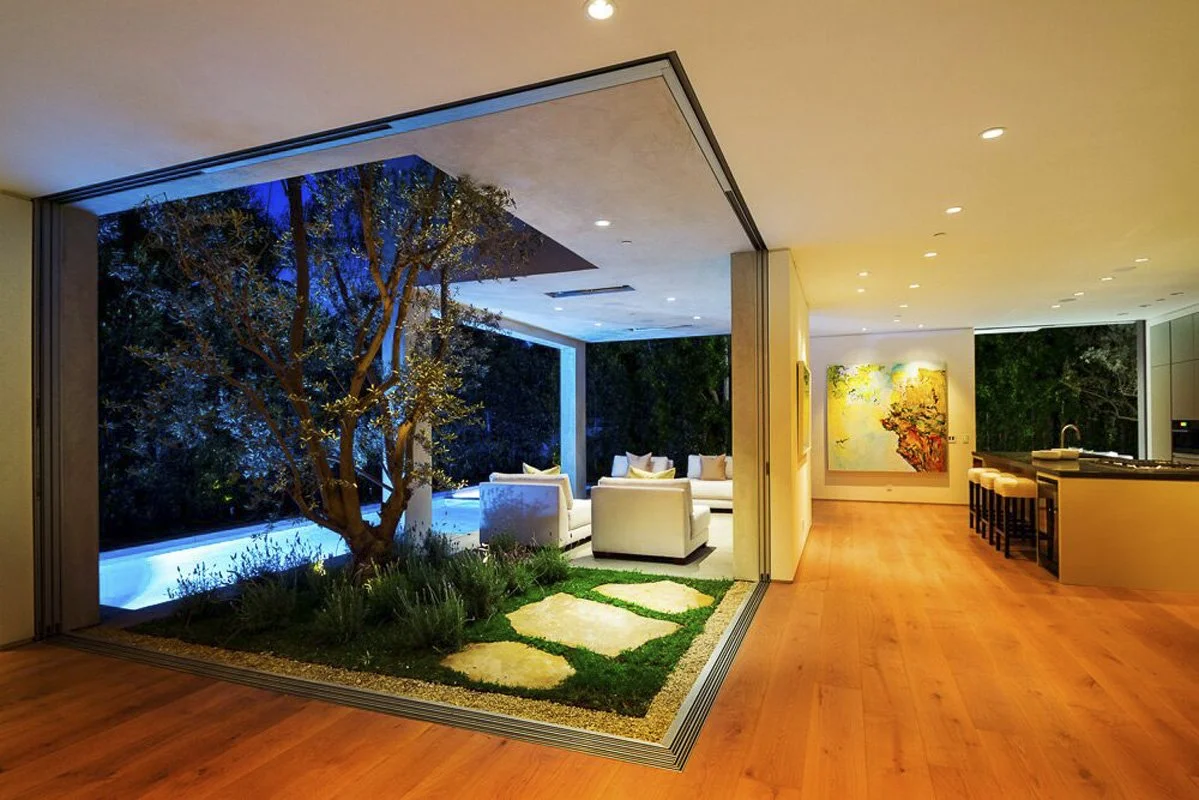 Courtyard view at night connecting living room and outdoor lounge in West Hollywood custom home.