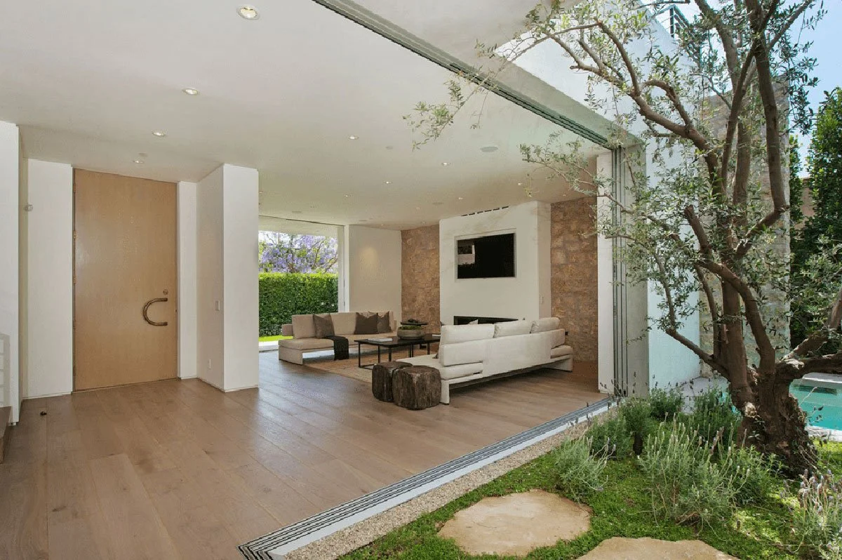 Modern indoor-outdoor living room in West Hollywood custom home opening to courtyard garden through sliding glass walls.