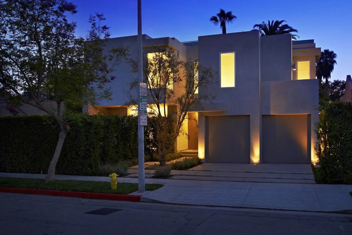 Front exterior of West Hollywood custom home at dusk with warm lighting and modern architecture.