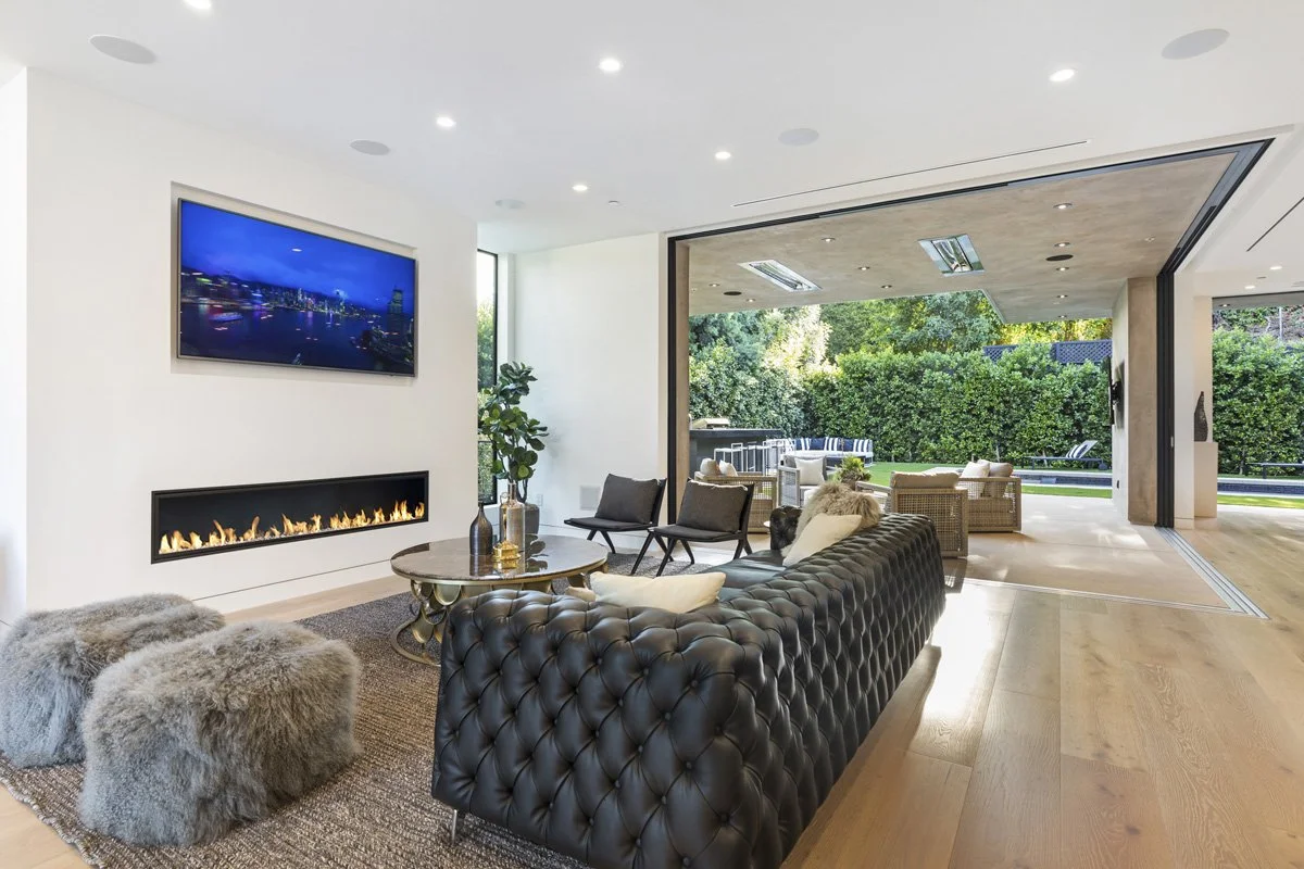 Beverly Hills living room with linear fireplace and full-height sliding glass walls opening to backyard