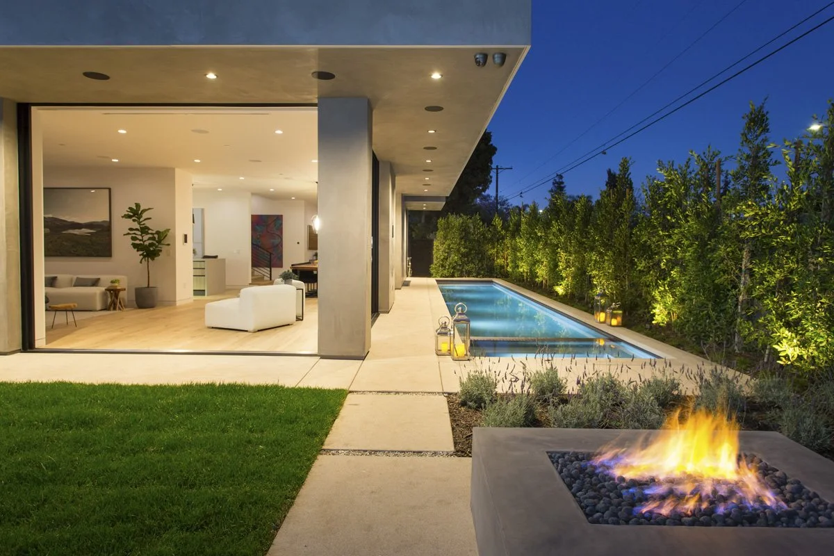 Modern Venice custom home with open indoor-outdoor living space, pool, fire pit, and contemporary architecture at dusk