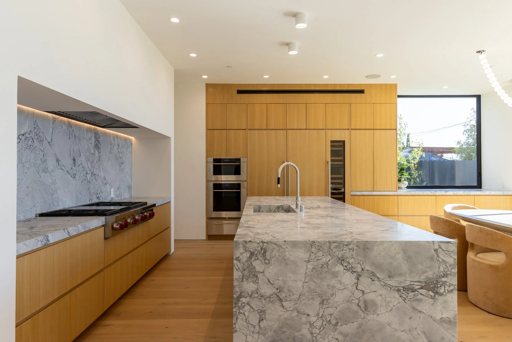 Modern Mar Vista kitchen with full-height custom oak cabinetry, marble waterfall island, integrated appliances, recessed lighting, and an open contemporary layout built by Heart Construction.