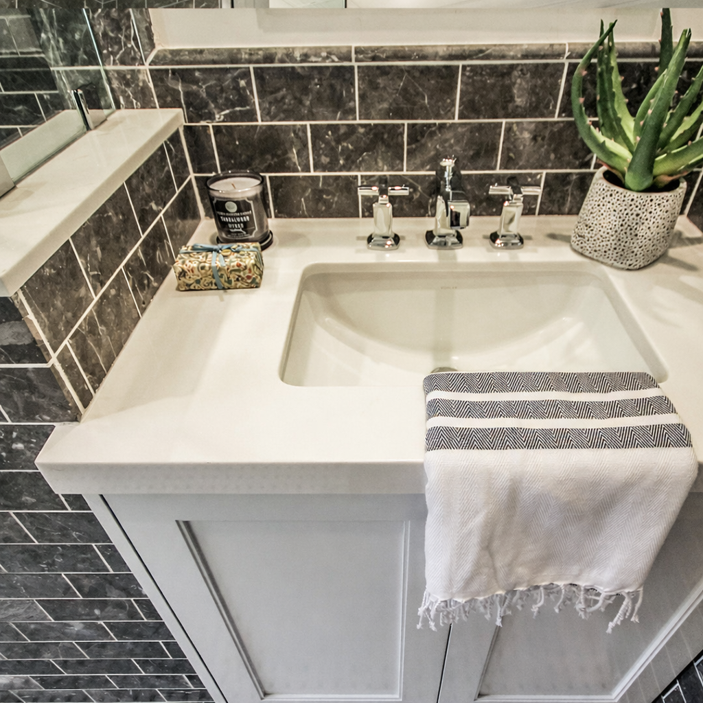 Spaulding Square bathroom vanity detail with white quartz countertop, undermount sink, chrome faucet, and dark tile backsplash in Los Angeles.