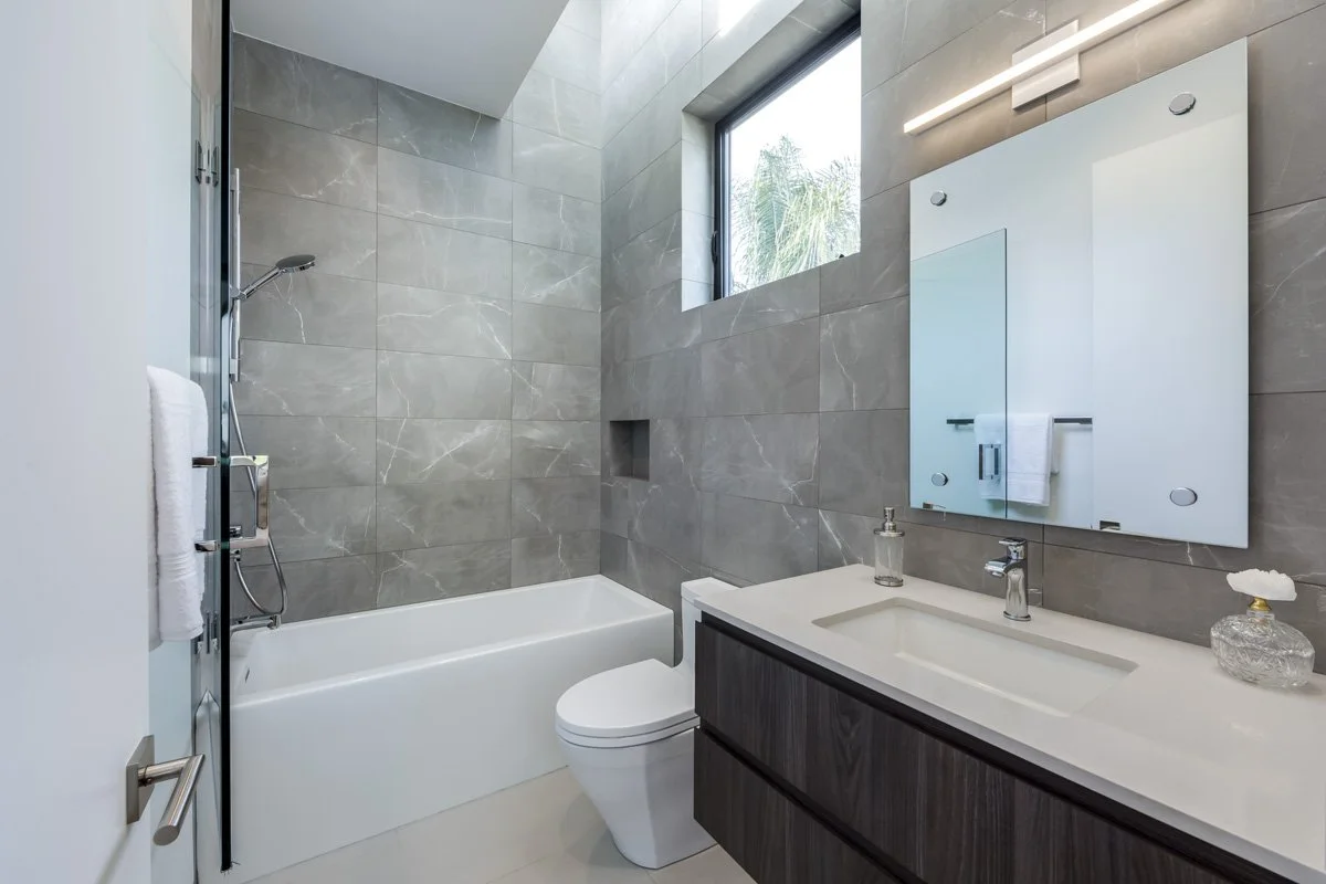 West Hollywood custom home bathroom with marble-look tile walls, floating vanity, and tub shower