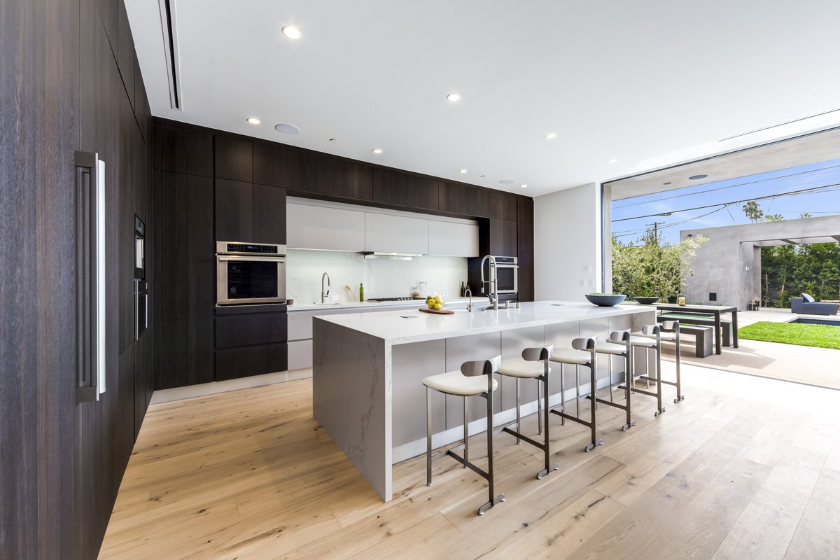 West Hollywood custom home kitchen with walnut cabinetry, waterfall island, and open backyard view