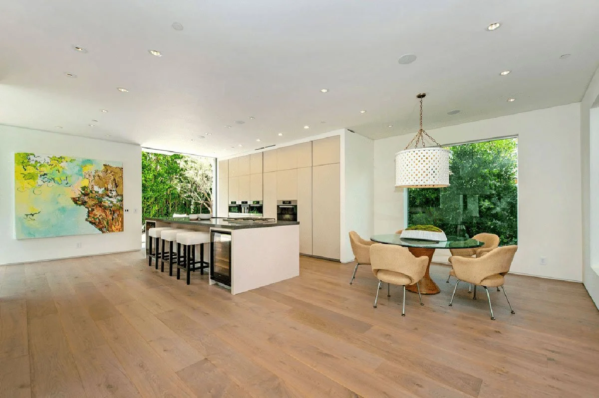 Open dining and kitchen area in West Hollywood modern home with garden-facing windows.