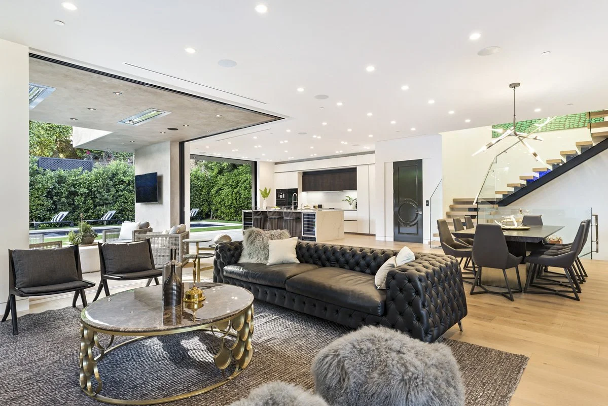 Beverly Hills open-concept living room with fireplace, dining area, and full-height sliding glass walls