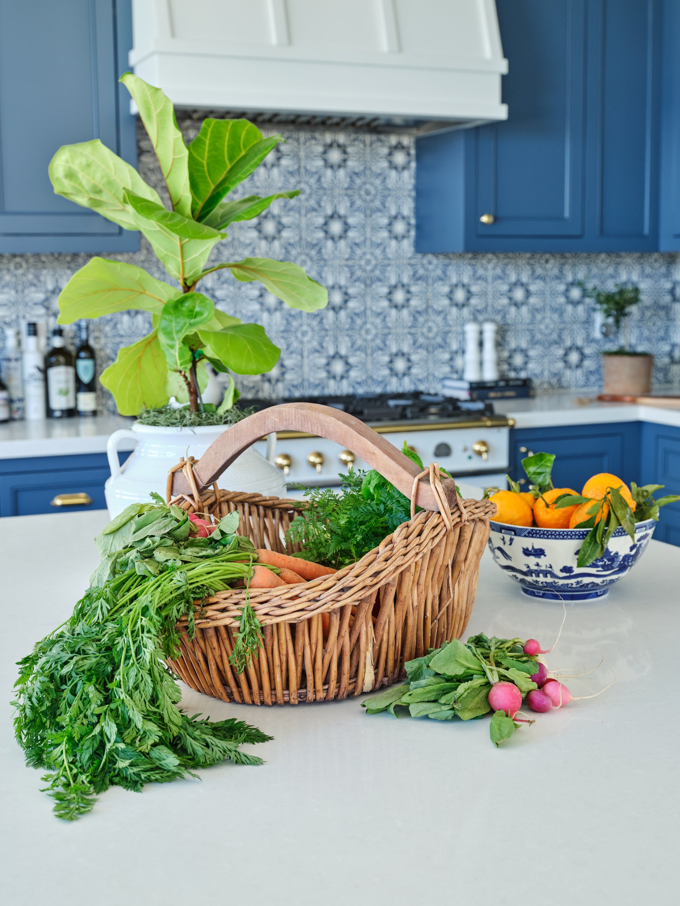 Malibu custom kitchen island with blue cabinetry, patterned tile backsplash, fresh produce styling, and handcrafted finishes by Heart Construction