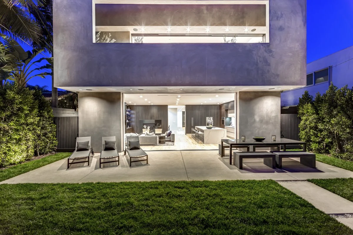 West Hollywood custom home with retractable glass walls opening to backyard patio and modern kitchen interior at night