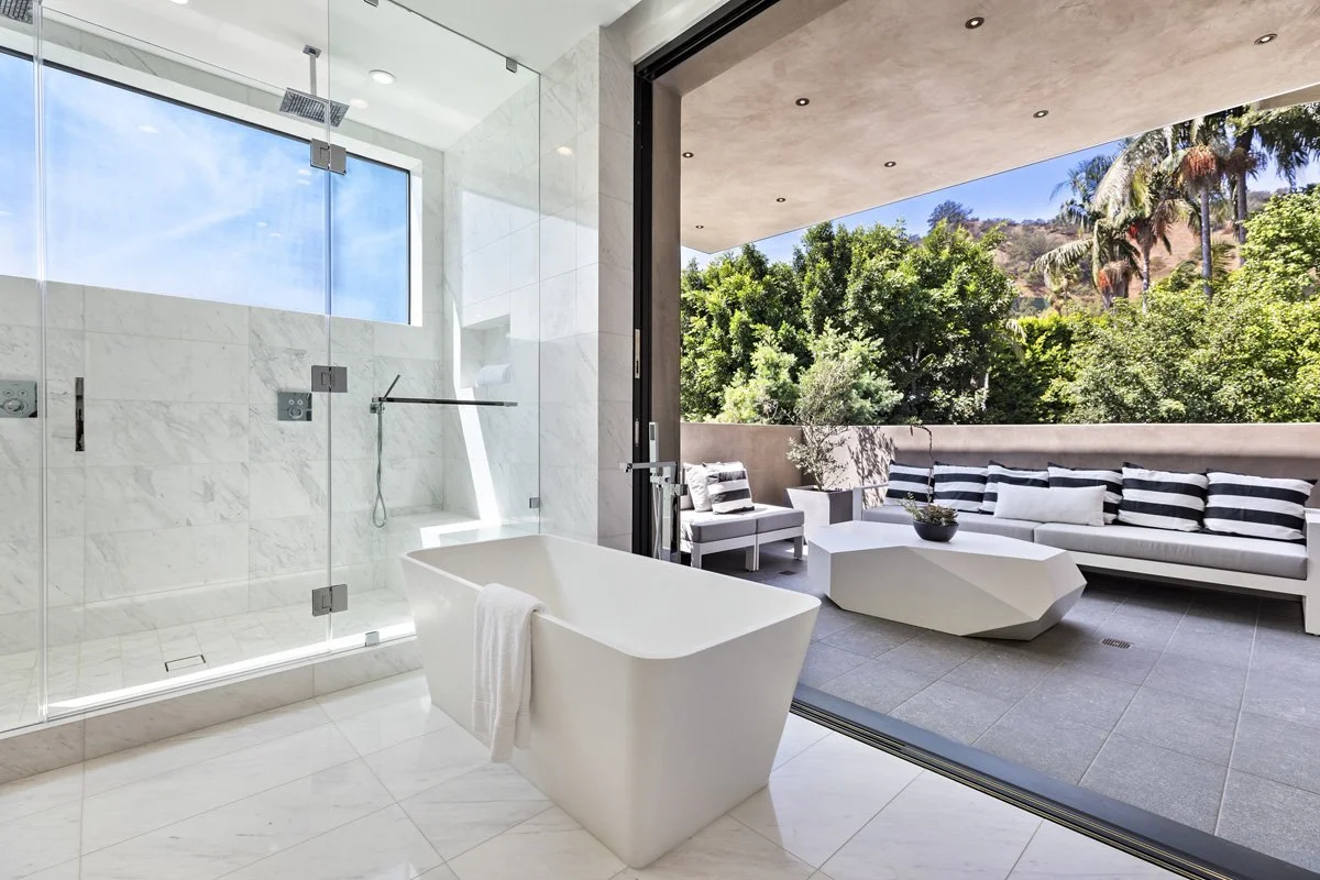 Beverly Hills indoor-outdoor bathroom design with sliding glass wall and covered terrace lounge