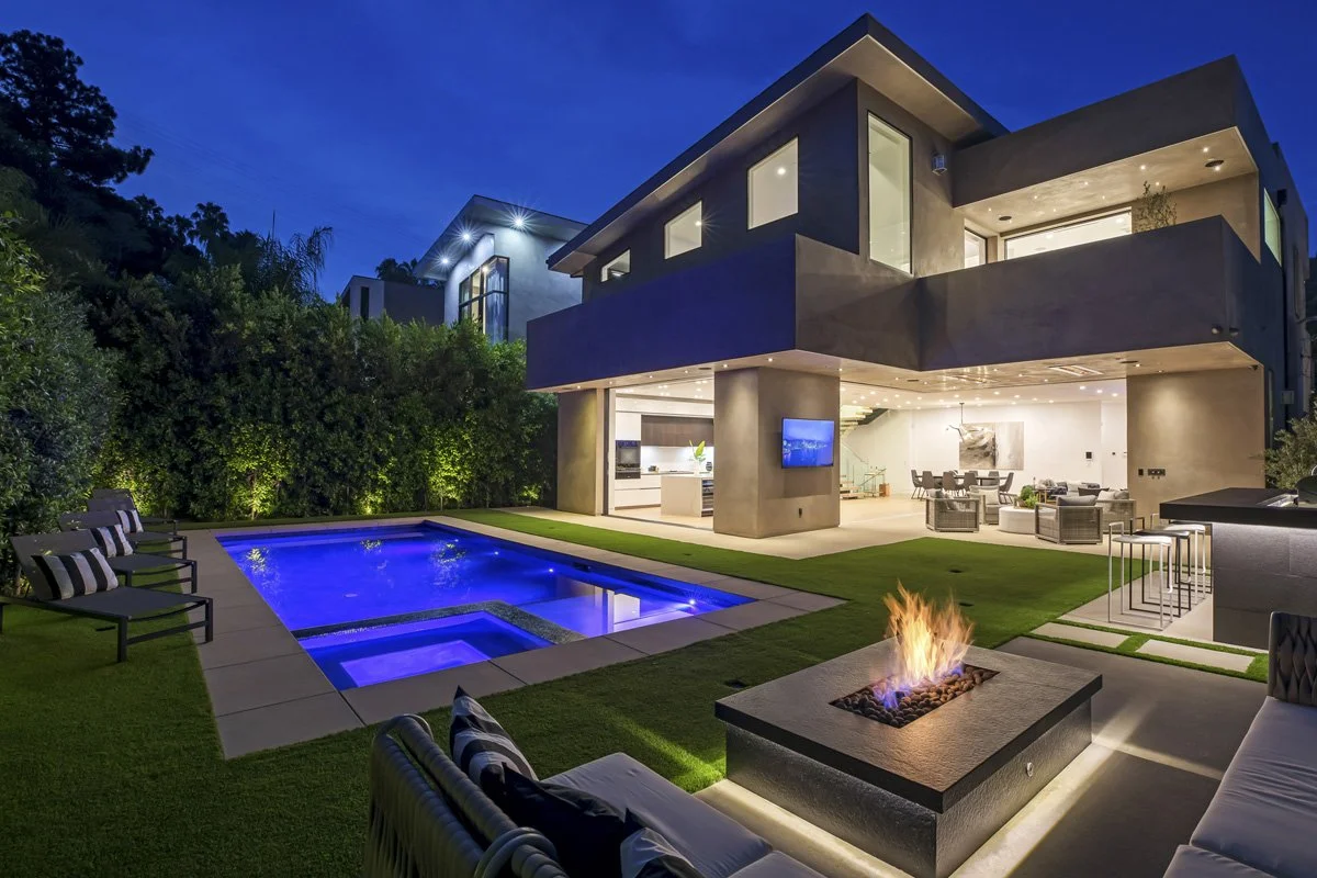 Pacific Palisades modern custom home with smooth stucco façade, black-framed windows, vertical wood garage door, and drought-tolerant landscaping.