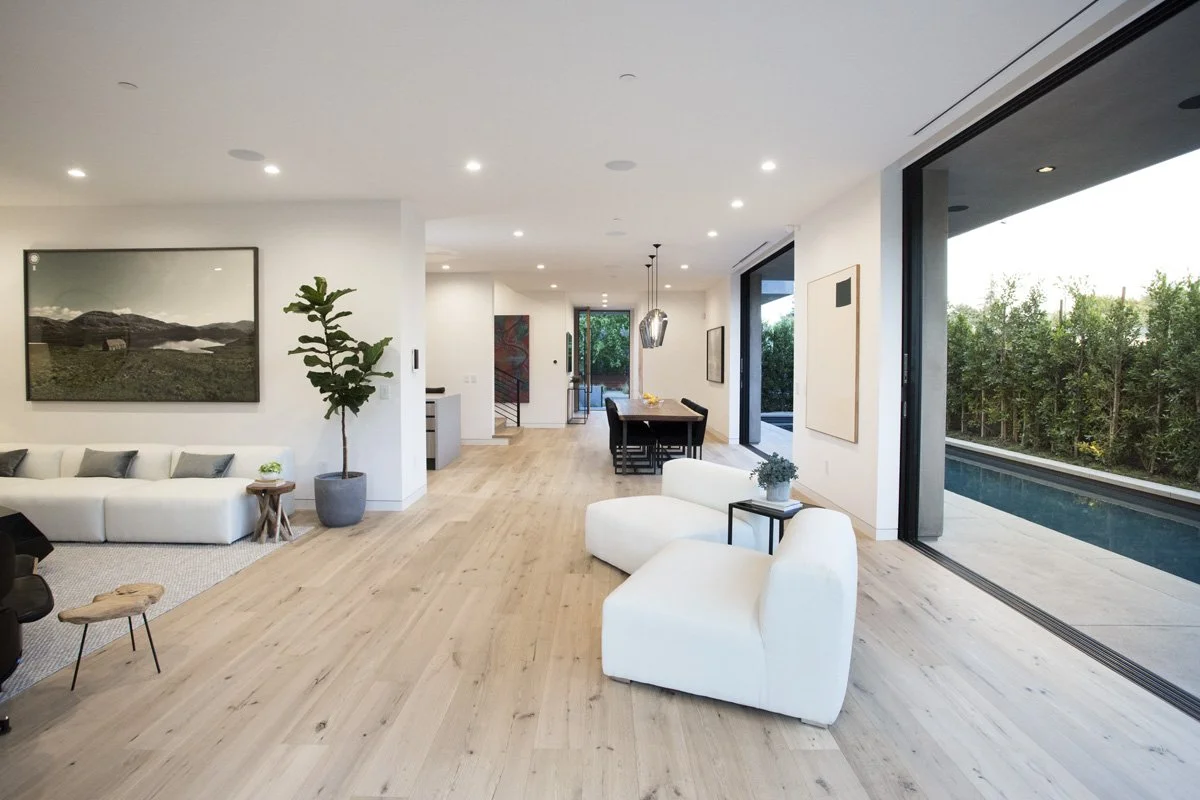 Venice open-plan living and dining area with wide-plank oak flooring, flush sliding door track, and linear lap pool connection