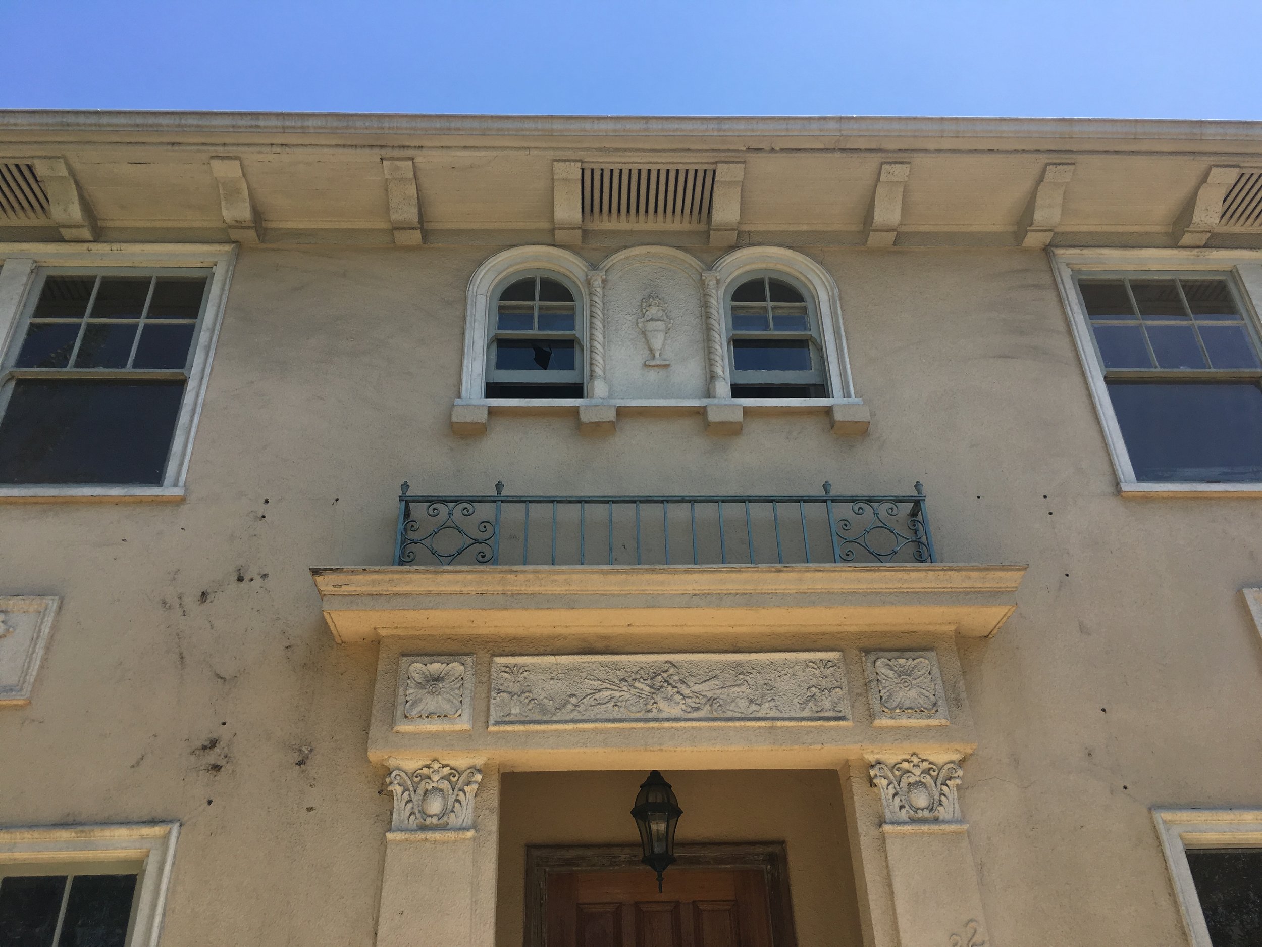 Hancock Park home before restoration front façade with original architectural detailing, balcony, and aging exterior condition