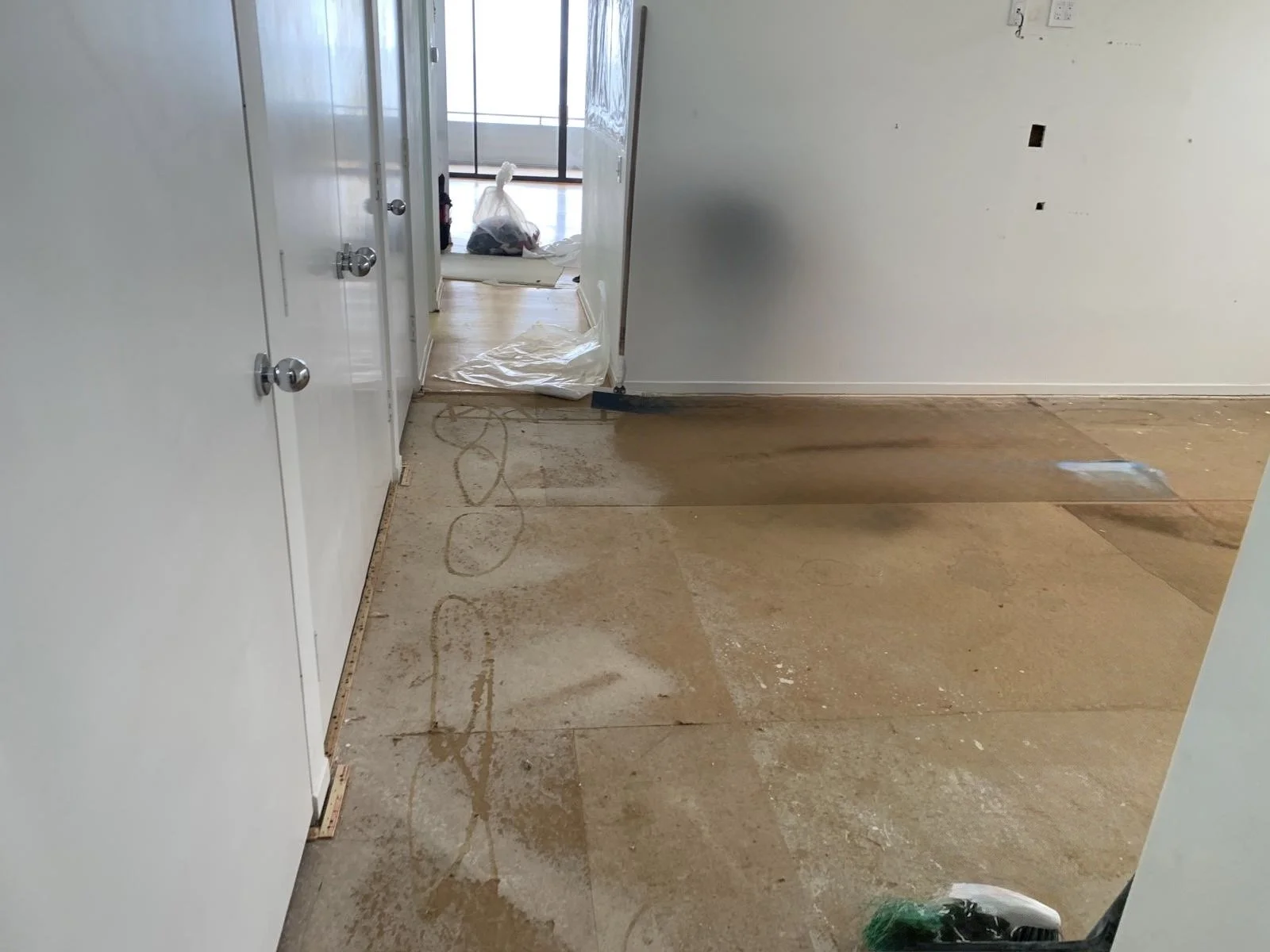 Malibu condo before renovation showing demolition phase with removed flooring, exposed subfloor, and entry hallway leading toward ocean-facing rooms