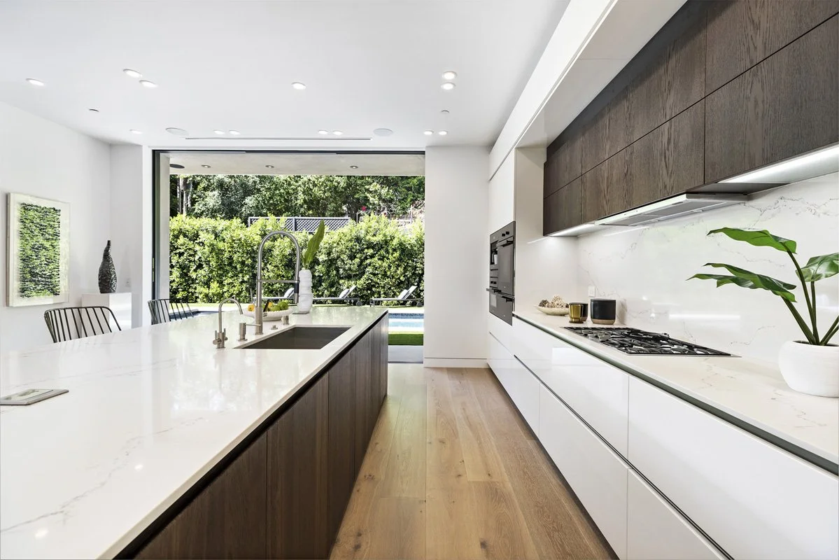 Modern Beverly Hills custom kitchen with waterfall island, integrated appliances, custom cabinetry, and seamless indoor-outdoor connection to backyard pool.