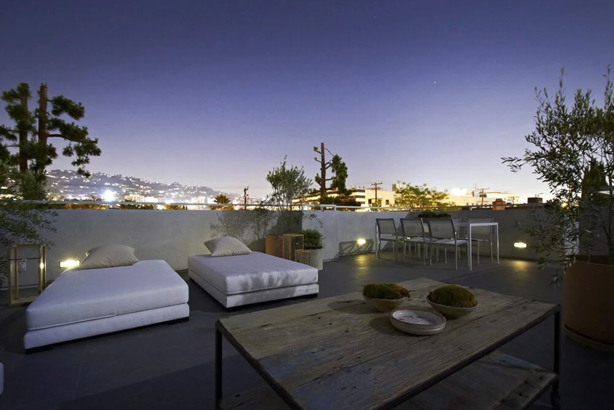 Rooftop terrace at night in West Hollywood modern residence with lounge seating and city lights.