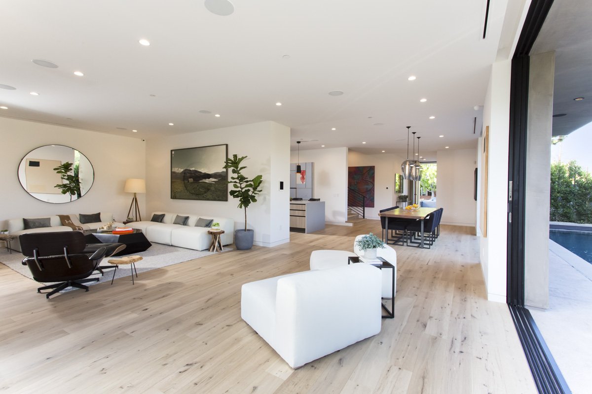 Open-concept living and dining space with wide plank wood flooring in modern Venice home